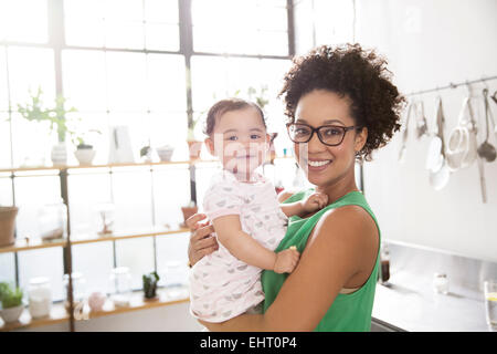 Mother holding her baby daughter in domestic kitchen Stock Photo