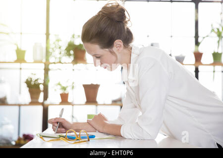 Young woman leaning at desk and writing Stock Photo