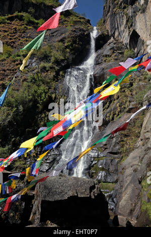 BHUTAN -Prayer flags by a waterfall near entrance to Taktshang Goemba, (Tiger's Nest Monastery), perched on the side of a cliff. Stock Photo