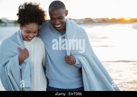 Portrait of couple wrapped in blanket on beach Stock Photo