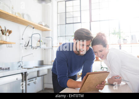 Young couple leaning at kitchen counter and looking at documents Stock Photo