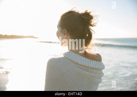 Young woman wrapped in blanket on beach Stock Photo