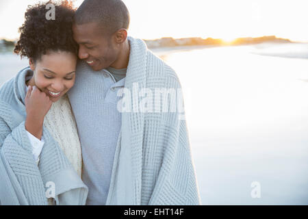 Portrait of couple wrapped in blanket on beach Stock Photo