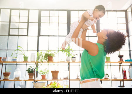 Mother lifting her daughter overhead Stock Photo
