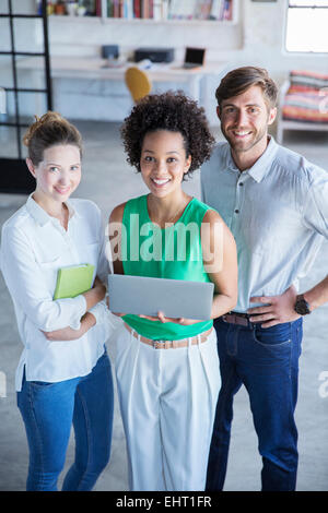 Portrait of three young people standing with digital tablet in studio Stock Photo