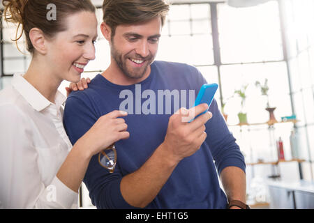 Two young people looking at mobile phone and smiling Stock Photo