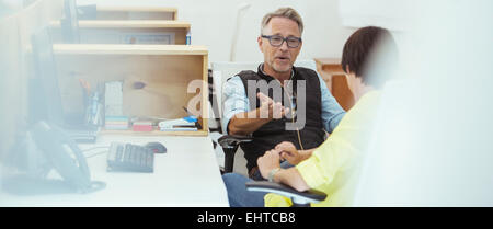 Two office workers talking at desk Stock Photo