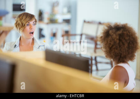 Female colleagues talking in office, feeling surprised Stock Photo