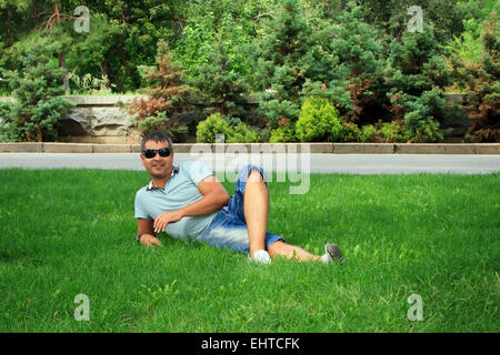 Happy young man relaxing on the green grass Stock Photo