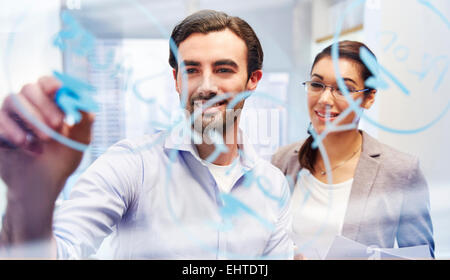 Office workers behind glass with blue marker writing on it Stock Photo