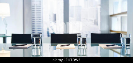 Part of modern conference room with table chairs,pens and glasses with water Stock Photo