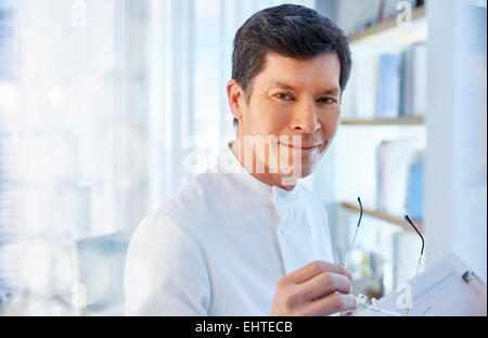 View of man in laboratory holding glasses looking at camera Stock Photo