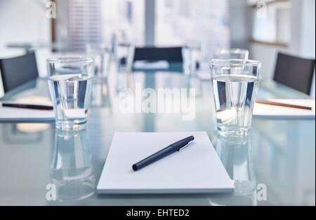 Part of modern conference room with table chairs, notepads, pens and glasses with water Stock Photo