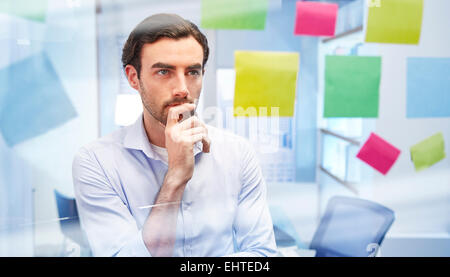 Office worker behind glass with colorful sticky notes thinking Stock Photo