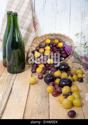 red and yellow plums on a wooden table with two bottle Stock Photo