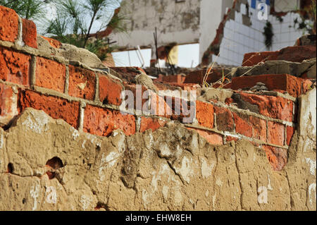 weathered exposed red bricks in damaged wall of old forsaken building Stock Photo