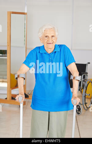Old woman with crutches smiling in physiotherapy room Stock Photo