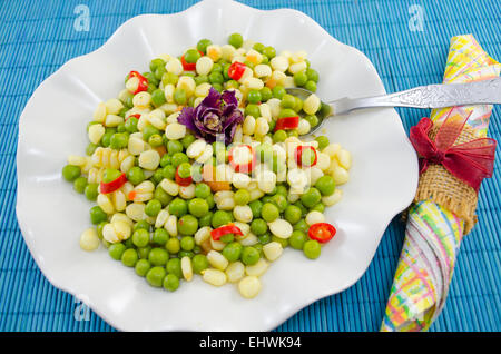 Plate set with cooked peas corn and pepper on a blue tablecloth Stock Photo