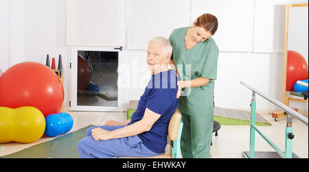 Senior man sitting with back pain in physical therapy with a physiotherapist Stock Photo