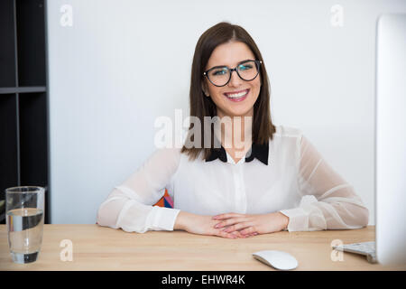 Cheerful businesswoman sitting at the table in office Stock Photo