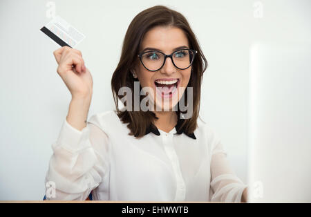 Surprised businesswoman sitting at the table with bank card Stock Photo