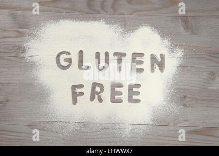 Word gluten free written in white flour on a old wooden table, vintage tone. Stock Photo