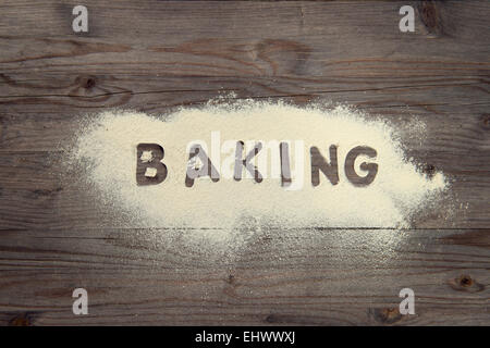 Word baking written in white flour on a old wooden table, low light vintage tone. Stock Photo