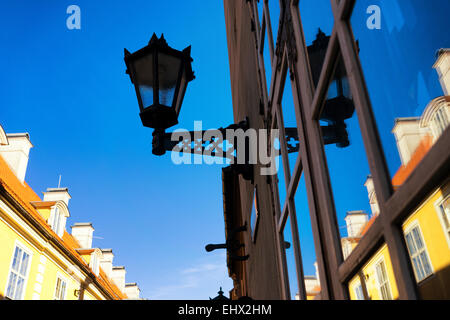 Street lamp on the facade of a residential building with reflection in windows on a background of blue sky Stock Photo