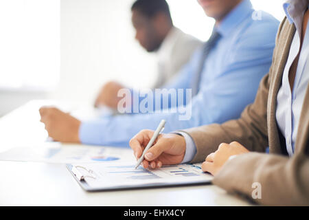 Row of people making notes on spreadsheet Stock Photo