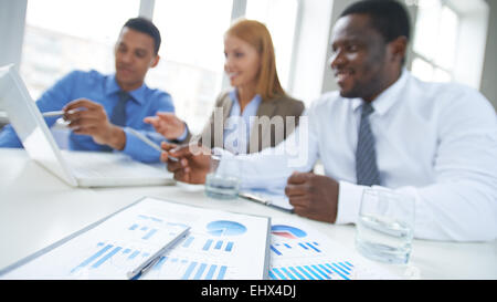 Close-up of reports on table with business people in the background Stock Photo