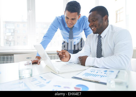 Two businessman discussing ideas on laptop Stock Photo