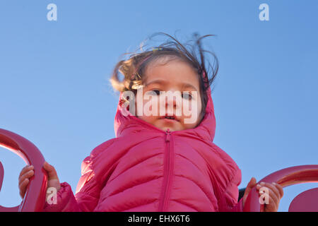 Adorable little on the top of the sledge in the playground a cold sunny day of winter Stock Photo
