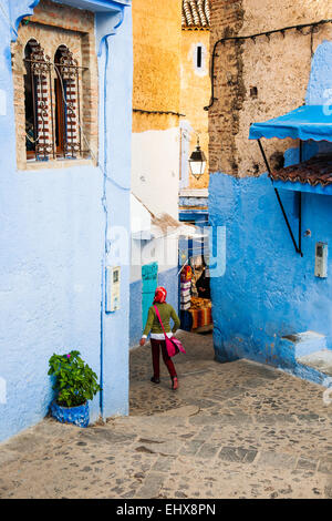 A local young woman walking on the blue-washed street of Chefchaouen, Morocco Stock Photo