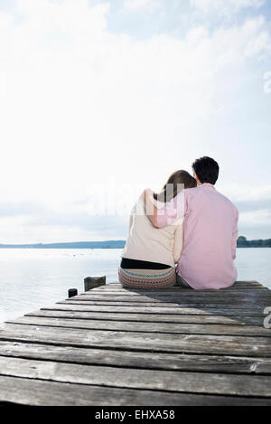 Couple hugging sitting lake jetty tranquil Stock Photo