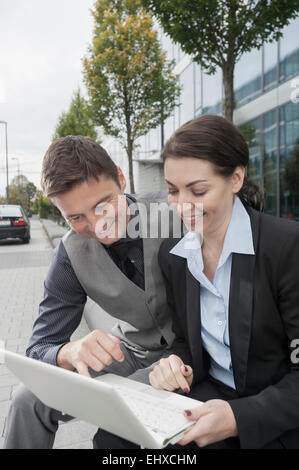 Two business executives working together on a laptop and smiling, Bavaria, Germany Stock Photo