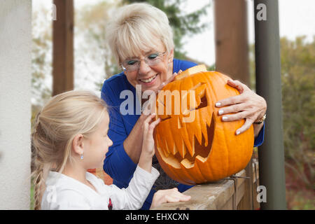 Senior woman showing Halloween pumpkin to her granddaughter, Bavaria, Germany Stock Photo