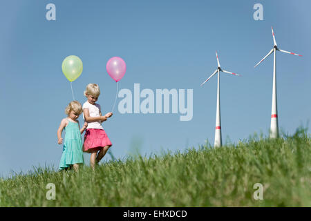 Two girls playing with balloons in windfarm, Bavaria, Germany Stock Photo