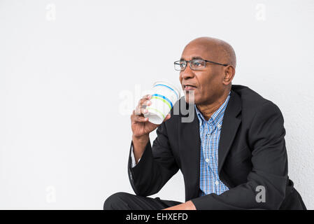 African businessman sitting drinking Coffee to go Stock Photo