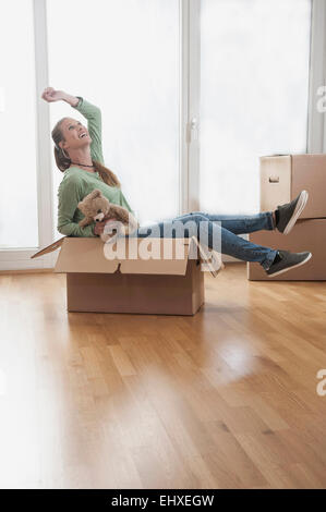 Cheerful Young woman sitting in a cardboard box, Bavaria, Germany Stock Photo