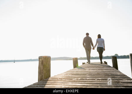 Couple walking on wooden jetty sunset