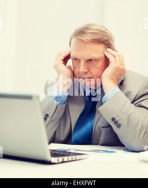 upset older businessman with laptop in office Stock Photo