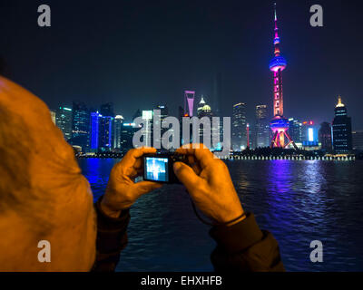 Elderly tourist taking photos of the Oriental Pearl Tower in Shanghai, China, with a small compact digital camera Stock Photo