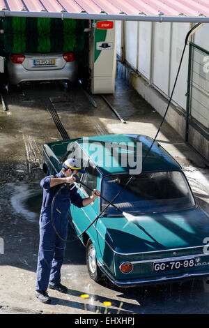 Young man washing car with high pressure water hose at a professional car wash Stock Photo