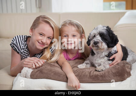 Two sisters with dog in a living room, Bavaria, Germany Stock Photo