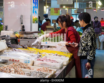 Costumer buying fish from a fishmonger at a market in Shanghai, China Stock Photo