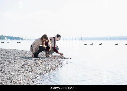Young couple lake shore gathering pebbles Stock Photo