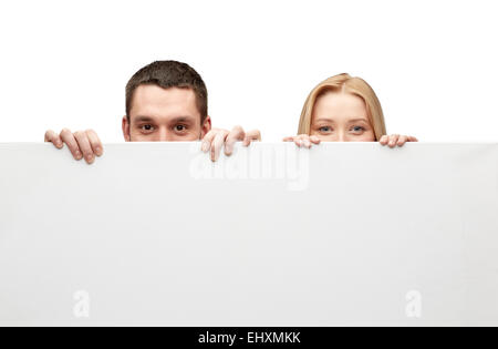 happy couple hiding behind big white blank board Stock Photo