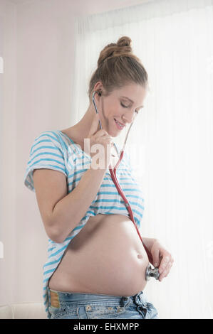 Pregnant woman stethoscope stomach listening Stock Photo