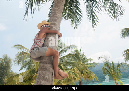 Teenage boy climbing palm tree, Koh Lipe, Thailand Stock Photo