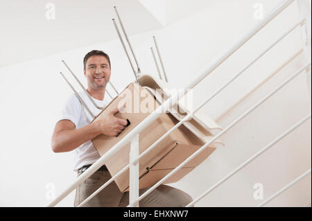 Man carrying moving box up staircase in new apartment, Bavaria, Germany Stock Photo